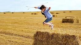 Boy jumping on hay